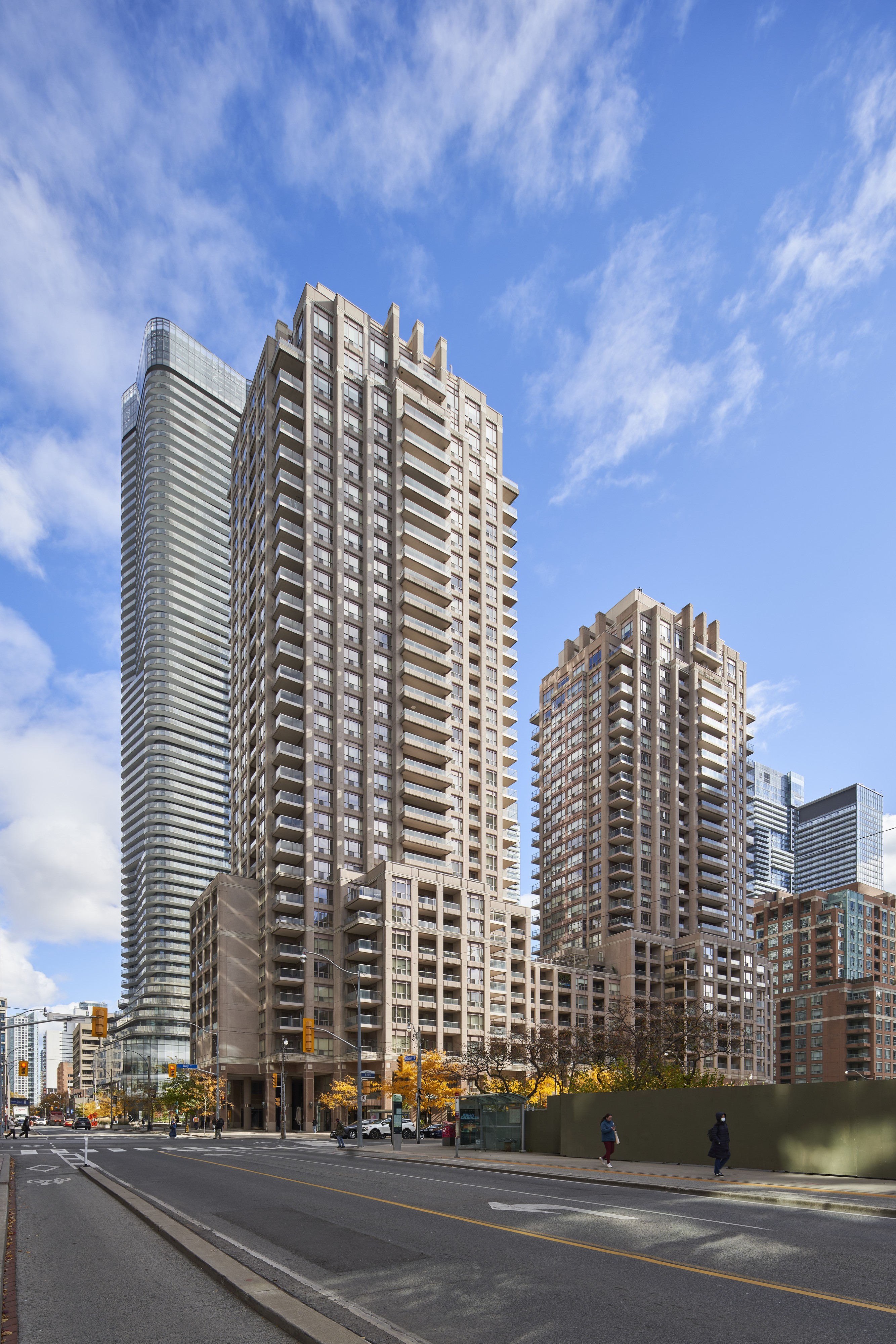 Two tall buildings stand next to each other with a street in front of them.